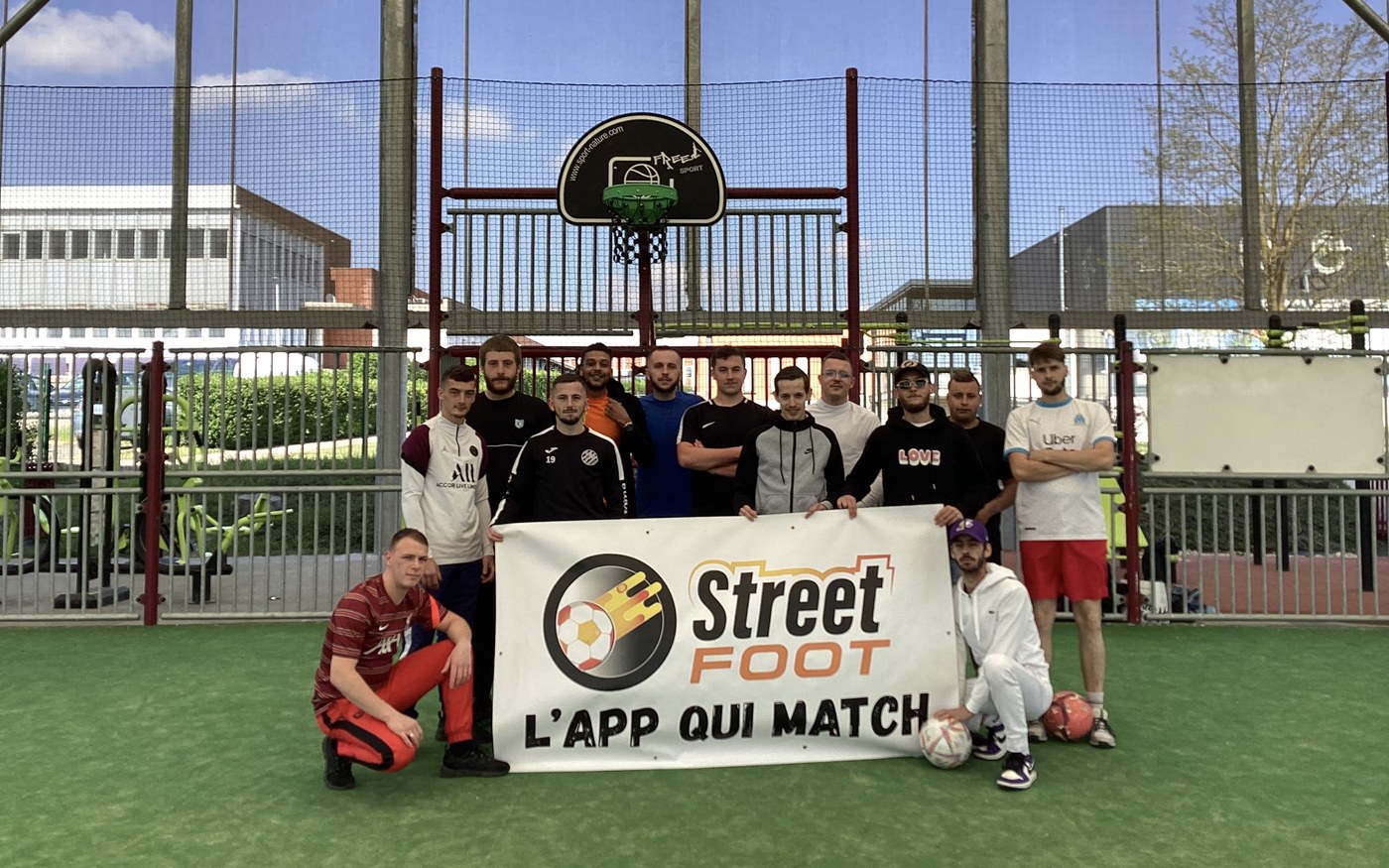 Groupe de joueurs StreetFoot posant avec la banderole « L'app qui match » sur un city stade.